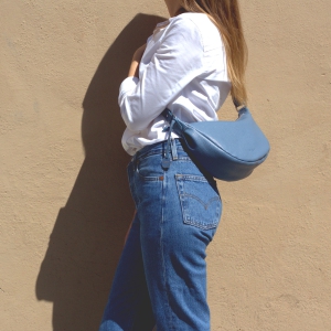 Mini leather crossbody bag in fairy blue color worn by a model, perfect small shoulder bag for women