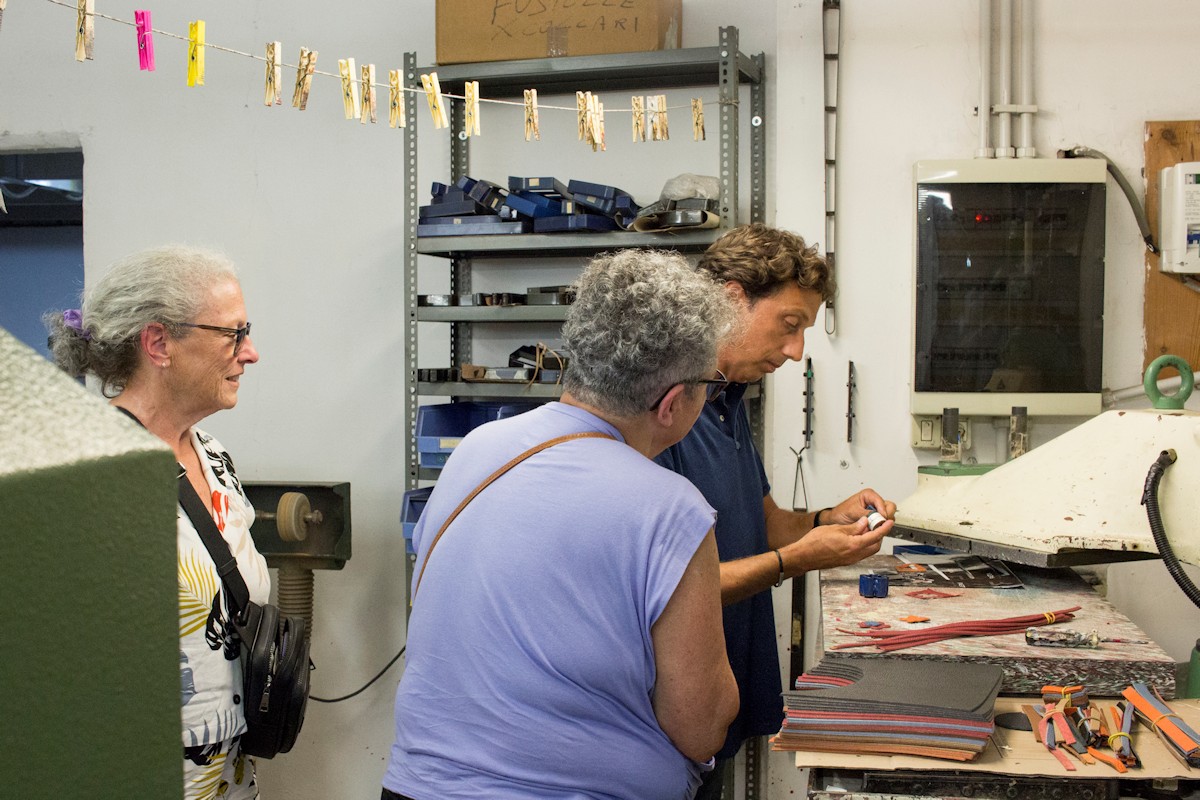 Artisan demonstrating leatherworking techniques to visitors at a Leather Workshop Tour in Rome, Italy.