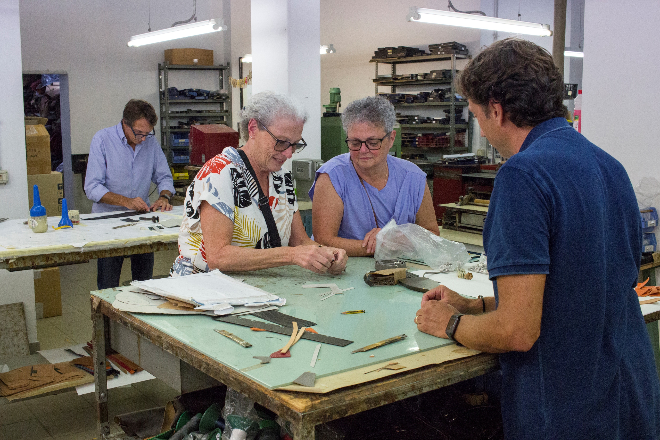 Visitors learning leather crafting skills during a Leather Workshop Tour in Rome. The intimate workshop setting showcases traditional tools and materials used in leather craftsmanship